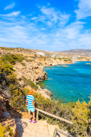 Young woman tourist standing on high cliff and looking at azure sea, Karpathos island, Greeceのeditorial素材