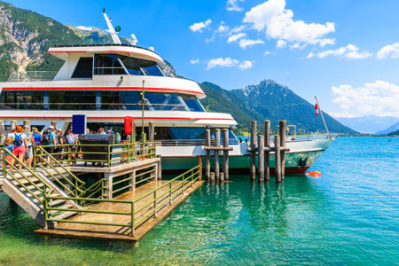 Tourists waiting to enter ship mooring at pier on shore of Achensee lake on sunny summer day, Pertisau, Tirol, Austriaのeditorial素材
