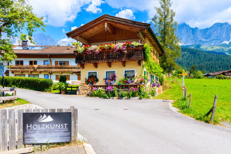 Traditional alpine houses in village of Going am Wilden Kaiser on beautiful sunny summer day with Alps mountains in background, Tirol, Austriaのeditorial素材