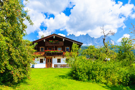 Traditional alpine house in village of Going am Wilden Kaiser on beautiful sunny summer day with Alps mountains in background, Tirol, Austriaのeditorial素材