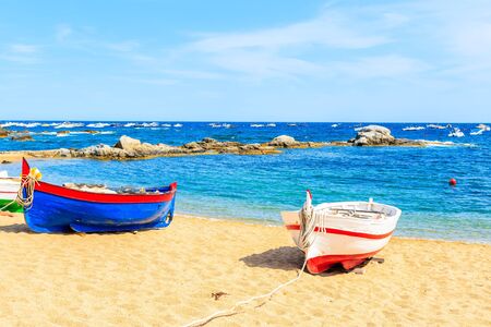 Traditional fishing boats on beach in Calella de Palafrugell, scenic village with white houses and...