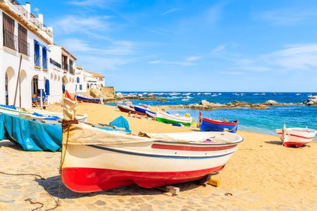 Traditional fishing boats on beach in Calella de Palafrugell, scenic village with white houses and sandy beach with clear blue water, Costa Brava, Catalonia, Spainのeditorial素材