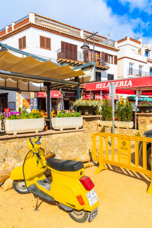 TOSSA DE MAR, SPAIN - JUN 6, 2019: Yellow classic scooter parking on beach in beautiful town of Tossa de Mar which is a seaside resort on Costa Brava, Spain.のeditorial素材