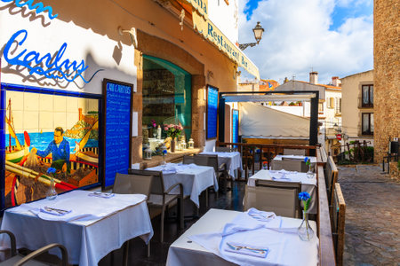 TOSSA DE MAR, SPAIN - JUN 6, 2019: Restaurant tables in old town of Tossa de Mar which is a seaside resort on Costa Brava, Spain.のeditorial素材