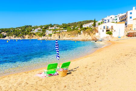 Sun chairs and umbrella on picturesque beach in Calella de Palafrugell village, Costa Brava,...