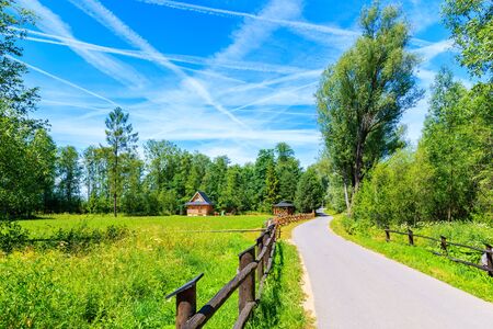 Cycling way along Dunajec river with wooden mountain house on green meadow on sunny summer day near...