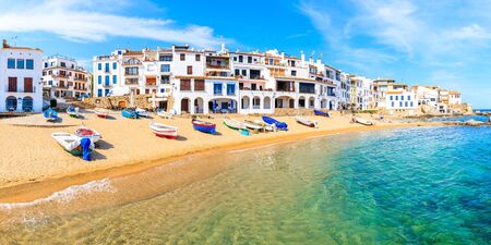 Panoramic view of fishing boats on beach in Port Bo with colorful houses of old town of Calella de...