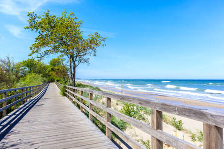 Wooden walkway along beautiful white sand beach with blue sea near Kolobrzeg, Baltic Sea coast, Polandの写真素材
