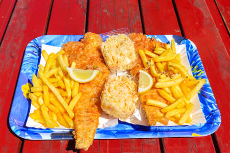 Fried cod fish with french fries and salad on wooden table in costal tavern in Ustronie Morskie port, Baltic Sea coast, Polandの写真素材