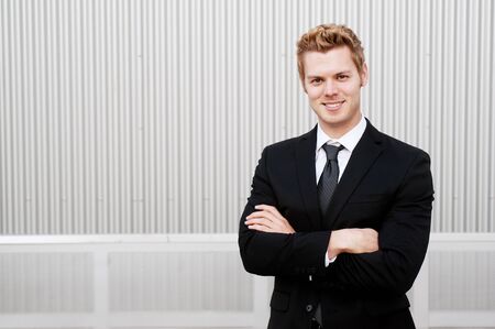 Portrait of a happy young businessman in suit standing outsideの写真素材