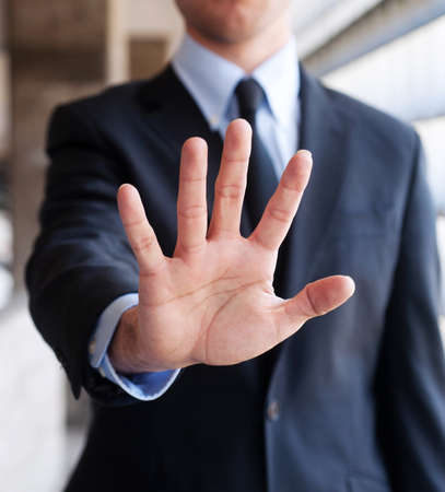 Business man holding out hand, making a hand gesture, indicating stopの写真素材