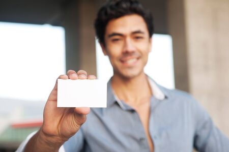Young handsome businessman presenting blank business cardの写真素材