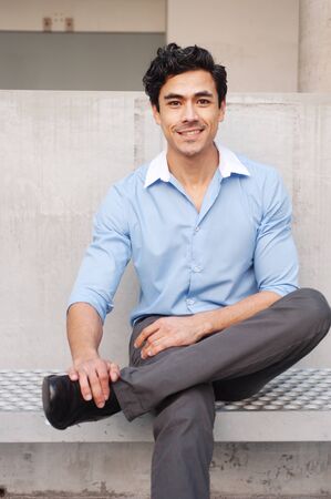 Handsome, young latino businessman sitting outsideの写真素材