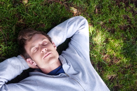handsome young man sleeping in the grass in a park
