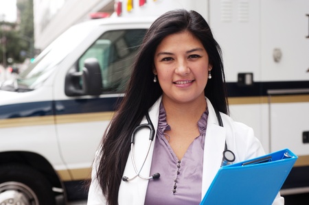 Portrait of young female doctor standing in front of an ambulance and holding a clipboardの写真素材