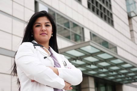 portrait of a young female doctor standing outside in front of a medical buildingの写真素材