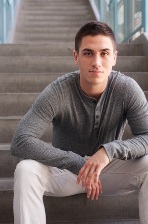 portrait of a handsome young man sitting on the steps inside a buildingの写真素材
