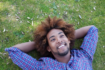 young, happy african american male lying in grassの写真素材