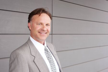 portrait of a confident mature businessman standing outside smiling at the camera