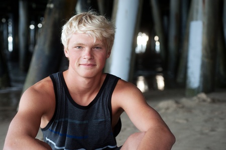portrait of a teenage surfer boy at the beach under the pierの写真素材
