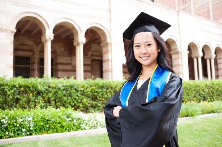 portrait of a beautiful young asian woman in graduation cap and gown standing outside on campusのeditorial素材