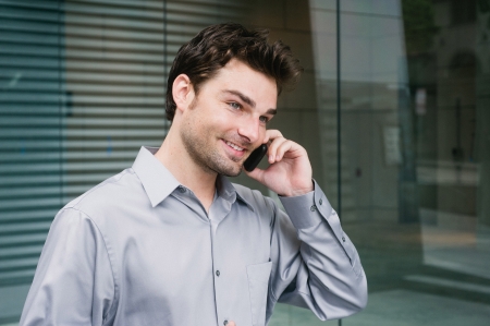 Portrait of a young businessman on the phone standing outside the officeの写真素材