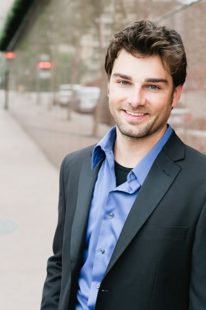 Portrait of a happy young businessman in suit standing outside officeの写真素材