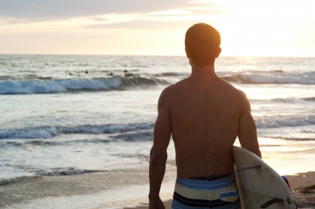 surfer sitting on the beach during sunsetの写真素材