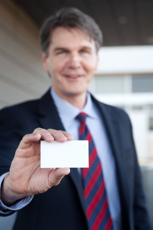 portrait of a confident mature businessman holding business cardの写真素材