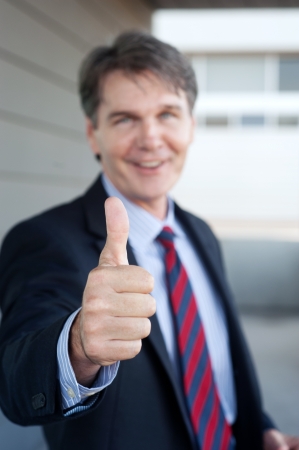 portrait of a confident mature businessman standing outside holding thumbs upの写真素材
