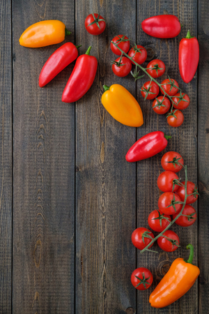 Peppers and cherry tomatoes on a wooden table. Space for text. Top view.の写真素材