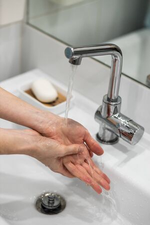 A woman washes her hands carefully with soapの写真素材