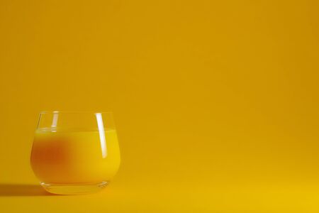 Glass with fresh orange juice on a yellow background.の写真素材