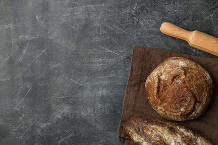 Rustic bread of whole wheat grains on dark background with copy space. Flat lay.