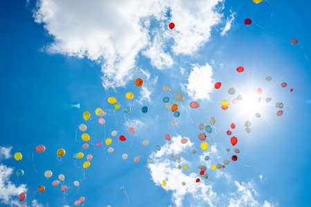 Colorful bright balloons in the blue sky with cloudsの写真素材