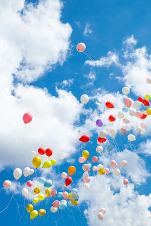Colorful bright balloons in the blue sky with cloudsの写真素材