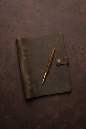 brown leather diary and pen on brown background or tableの写真素材