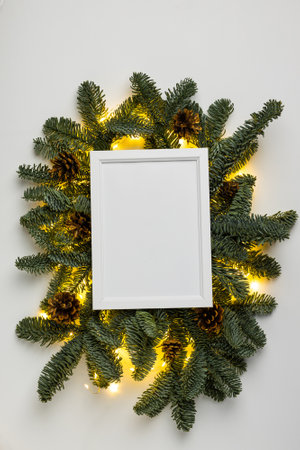 Empty white border with garland of fir branches and cones and lights on a white backgroundの写真素材