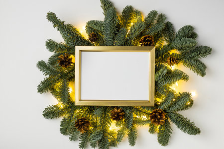 Empty golden border with garland of fir branches and cones and lights on a white backgroundの写真素材