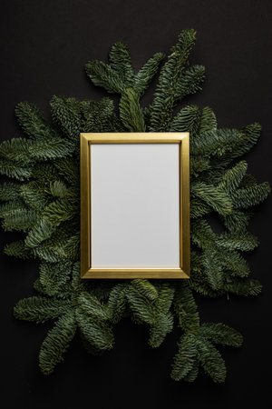 Empty golden border with garland of fir branches and cones on a black background.の写真素材