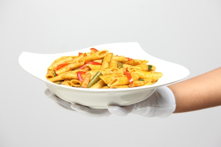 A person holding a bowl of pasta with pepper sauce