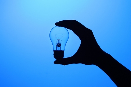 Hand holding a bulb with a blue backgroundの写真素材