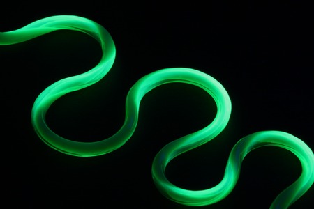 Green plastic straw under black lightの写真素材