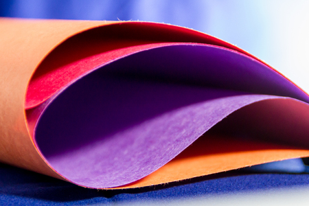 Close-up of multi colored paper with blue background