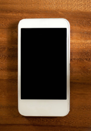 White smart phone with isolated screen on old wooden deskの写真素材