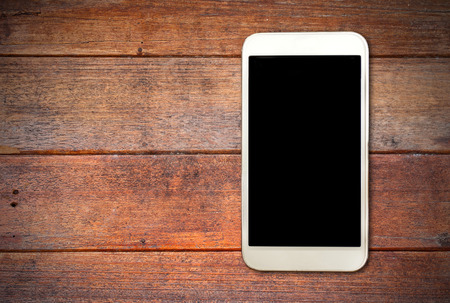White smart phone with isolated screen on old wooden deskの写真素材