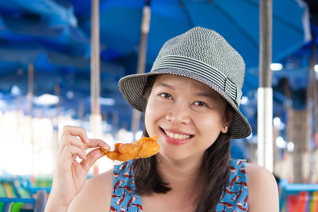 Woman eating seafood outside in summer smiling happy at camera. Asian Caucasian girl eating healthy fresh seafood.の写真素材