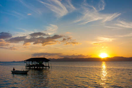 silhouette home against sunset in the seaの写真素材