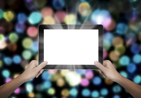 Female hand holding tablet pc on colorful bokeh backgroundの写真素材
