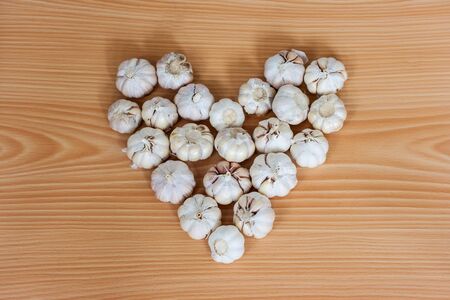 white garlic in the heart shape on wooden backgroundの写真素材